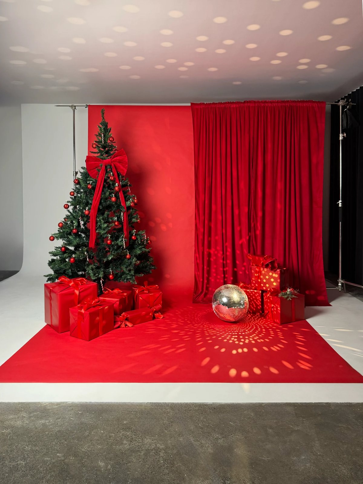 Red paper backdrop with a velvet curtain, styled as a Christmas set