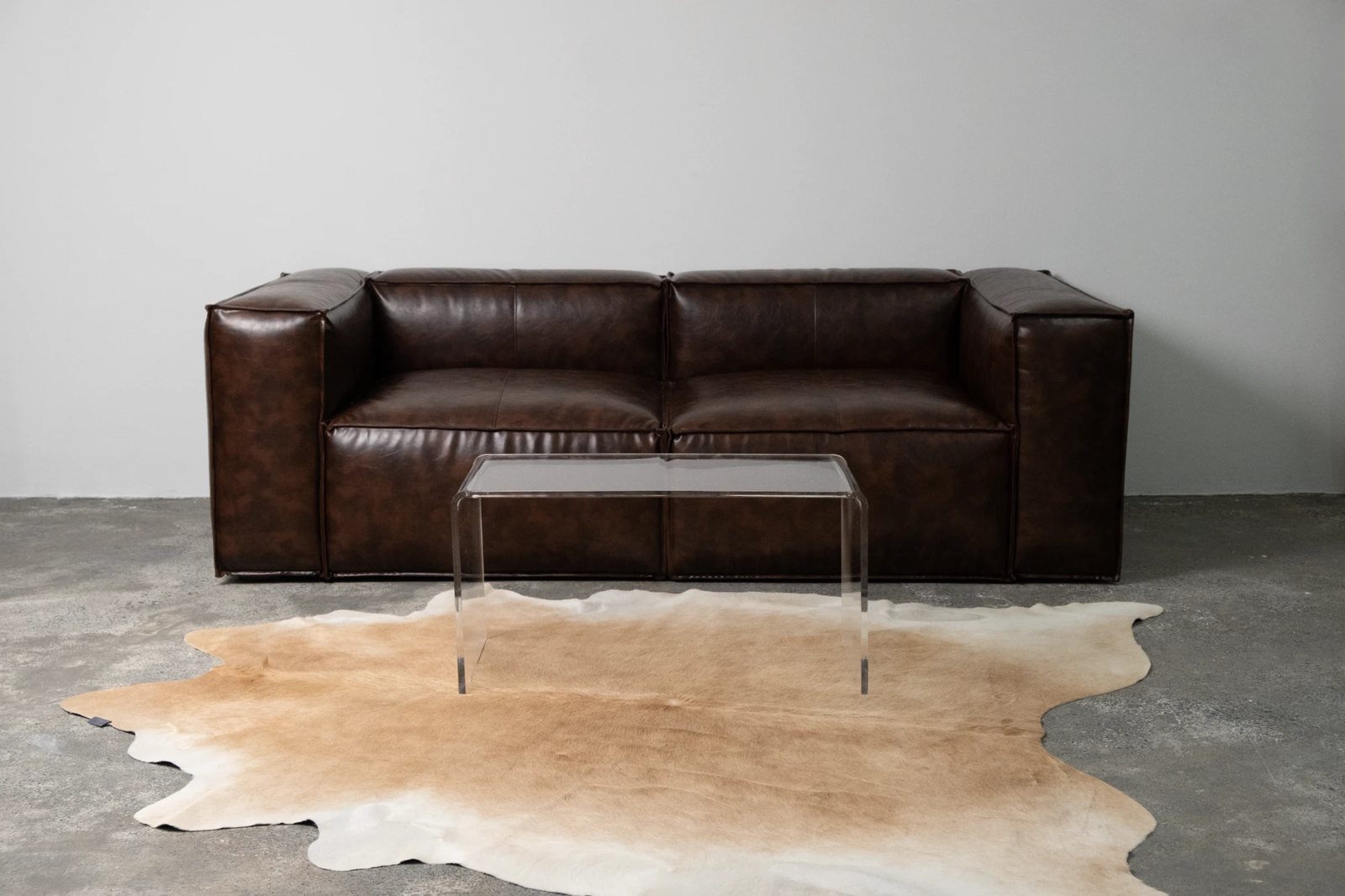 Brown leather sofa, acrylic table and cowhide rug at Tundra Studio