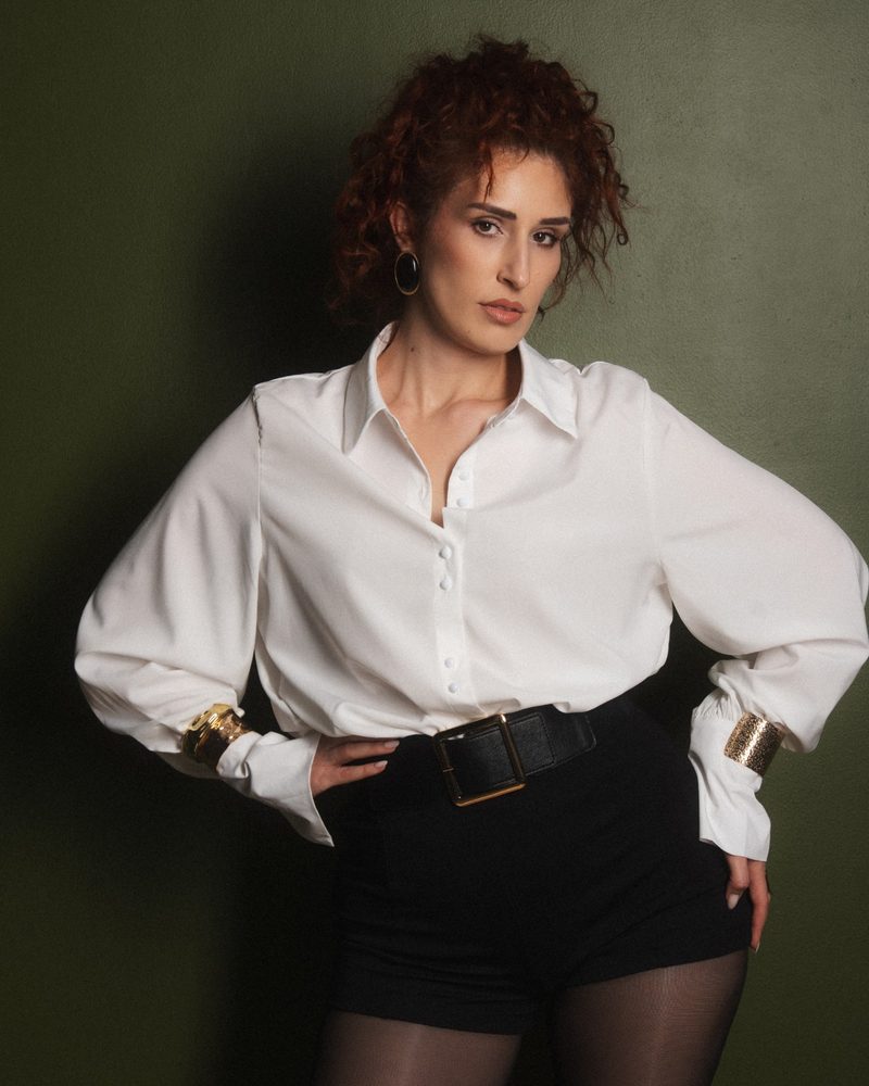 Portrait of a woman in a white shirt against the studio's green wall